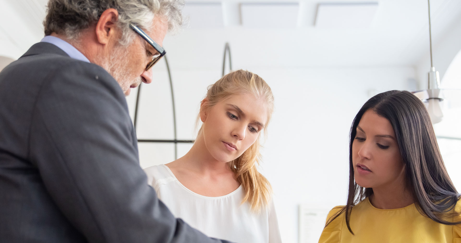 man in suit conferring with two women over unseen document